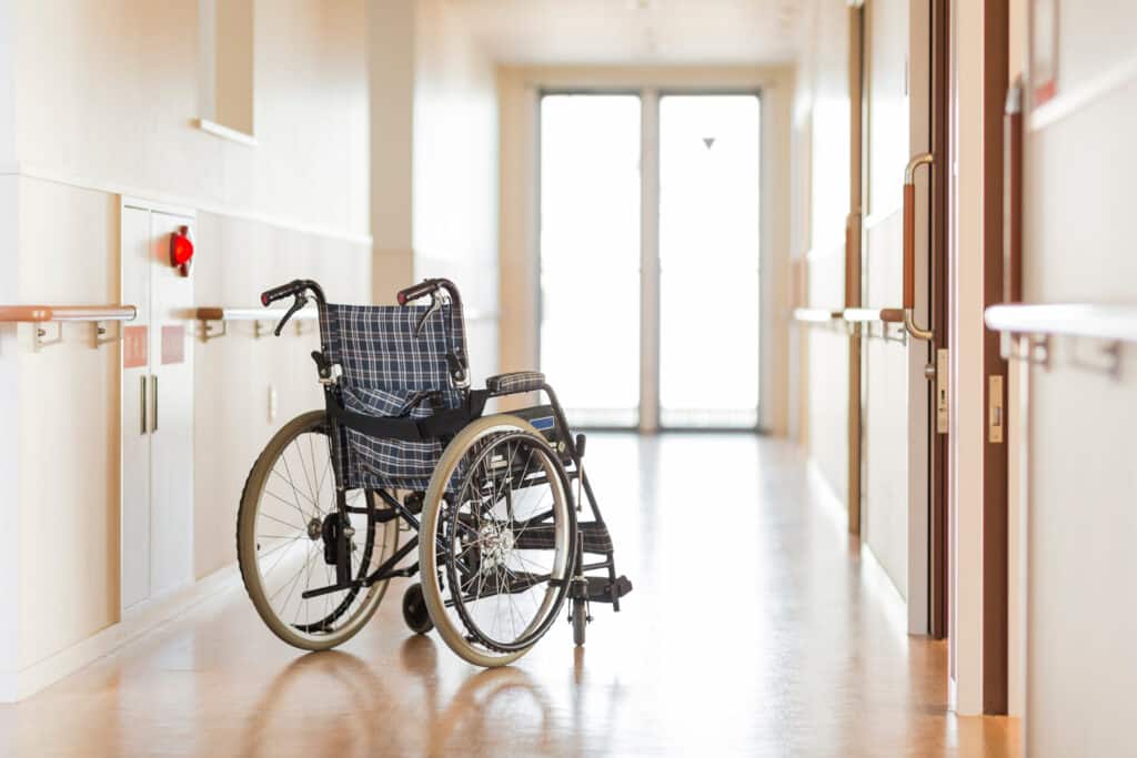 Empty wheelchair in a clean healthcare hallway, emphasising strict hygiene and pest control standards in an aged care or hospital setting.